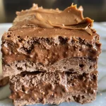['Close-up view of chocolate protein frosting in a bowl with a creamy texture.', 'Side view of thick, rich chocolate protein frosting ready to spread.', 'Chocolate frosting made with protein powder, showing a glossy finish.', 'Delicious chocolate protein frosting in a small dish, highlighting its smooth consistency.']