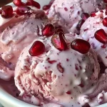 ['Close-up view of creamy pomegranate ice cream with vibrant seeds.', 'Side perspective of a bowl filled with pomegranate ice cream, highlighting its texture.', 'Juicy pomegranate ice cream topped with fresh arils against a contrasting background.', 'Detailed shot of pomegranate ice cream, showcasing the rich color and texture.']