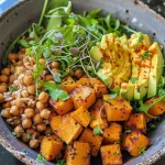 ['Close-up of a Roasted Butternut Squash Buddha Bowl with vibrant vegetables.', 'A colorful Buddha Bowl featuring roasted butternut squash, greens, and avocado slices.', 'Side view of a healthy Buddha Bowl filled with cubed butternut squash and microgreens.', 'Detailed image of a filled bowl with roasted squash, arugula, and tahini drizzle.']