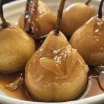 ['Close-up view of poached pears in a bowl, showing their juicy texture and caramelized surface.', 'Side view of slow cooker poached pears glistening in a rich syrup, sourced from an iPhone 15 Pro photo.', 'Juicy Bosc pears in a slow cooker with apple juice and spices, captured in a detailed close-up.', 'A delectable arrangement of poached pears with cinnamon sticks, highlighting their soft, tender appearance.']