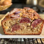 ['Close-up view of freshly baked fig bread with visible fig pieces and nuts.', 'Side angle of a golden brown loaf of fig bread, showcasing its texture and ingredients.', 'A delicious slice of fig bread displaying chunks of figs and walnuts on a wooden surface.', 'A moist fig bread loaf, emphasizing the rich, dark color of the figs and spices.']