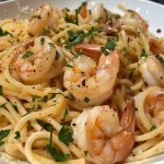 ['Close-up view of a vibrant shrimp pasta dish with garlic and herbs.', 'Side angle of delicious shrimp pasta garnished with parsley and cheese.', 'Juicy shrimp pasta with a glistening garlic sauce and lemon zest.', 'A hearty bowl of linguine topped with succulent shrimp and spices.']
