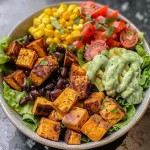 ['A close-up side view of a vibrant Vegan Southwest Sweet Potato Bowl, showcasing colorful ingredients.', 'Juicy Vegan Southwest Sweet Potato Bowl filled with black beans, corn, and cherry tomatoes.', 'A side view of a delicious Vegan Southwest Sweet Potato Bowl, highlighting cubed sweet potatoes and fresh greens.', 'An appetizing Vegan Southwest Sweet Potato Bowl featuring a mix of ingredients like cashews and cilantro.']