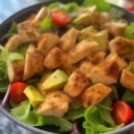 Close-up view of a colorful turkey salad featuring avocado and cherry tomatoes.