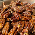Close-up view of shiny candied pecans glistening with caramel.