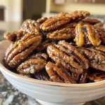 Close-up of golden brown Curry Candied Pecans on a white plate.