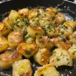 Close-up view of freshly made gnocchi on a wooden surface, lightly dusted with flour.